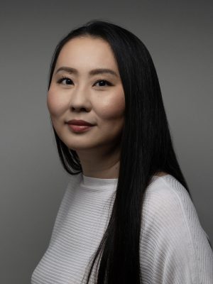 Sachie Ueshima, wearing white in front of a gray background.